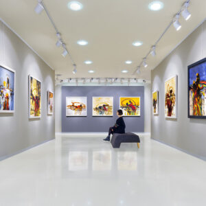 In a art gallery young woman visits an art exhibition and looks at artist's collection.