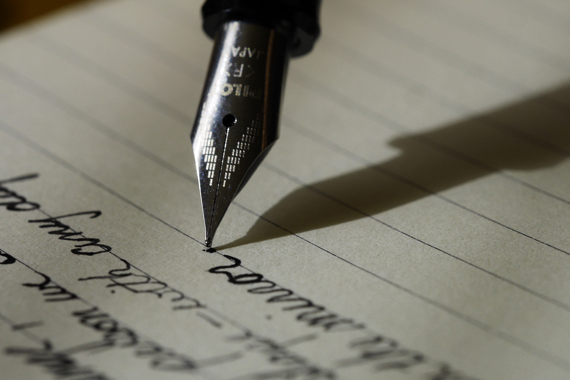 A fountain pen writing on a piece of lined paper that could be used to write an artist bio