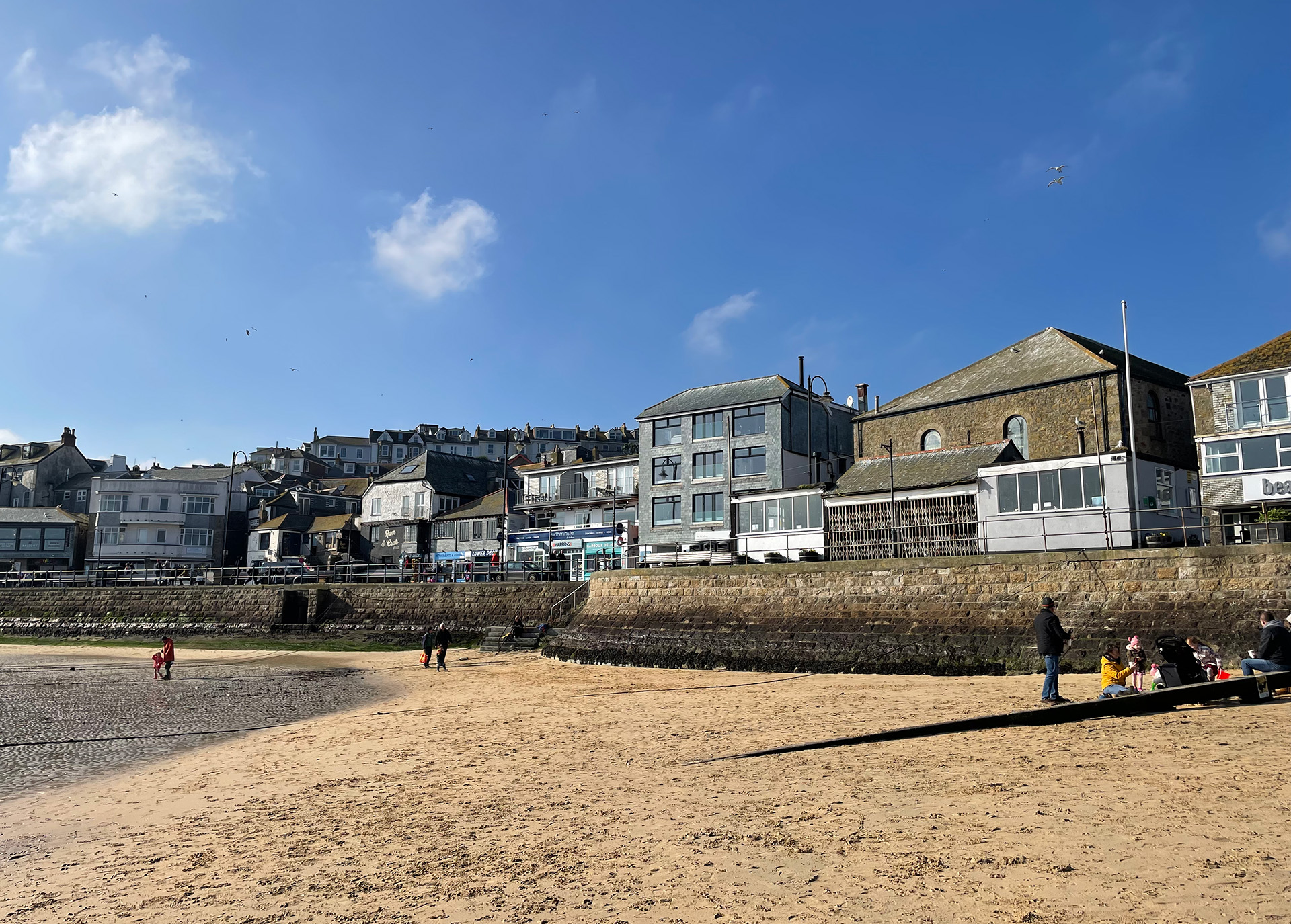 A picture of St Ives harbour with beautiful blue skies and sandy beach.